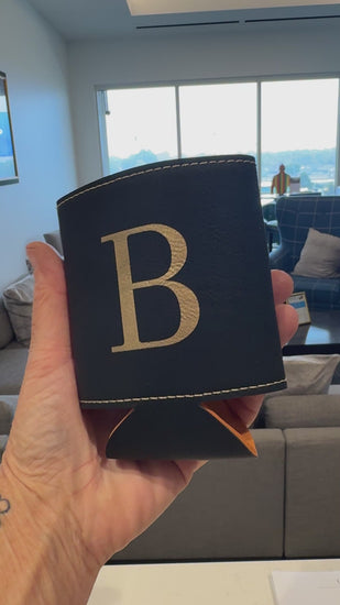 Personalized black leatherette can beverage holder with engraved gold initial at live event