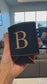 Personalized black leatherette can beverage holder with engraved gold initial at live event
